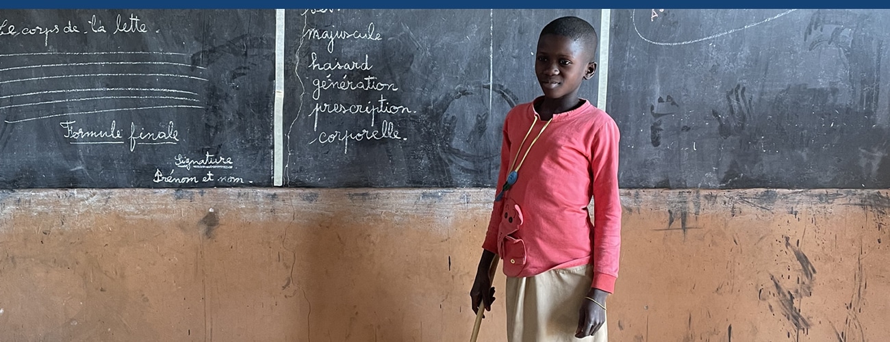 Jeune fille bénéficiaire du Bénin devant un tableau noir à l'école