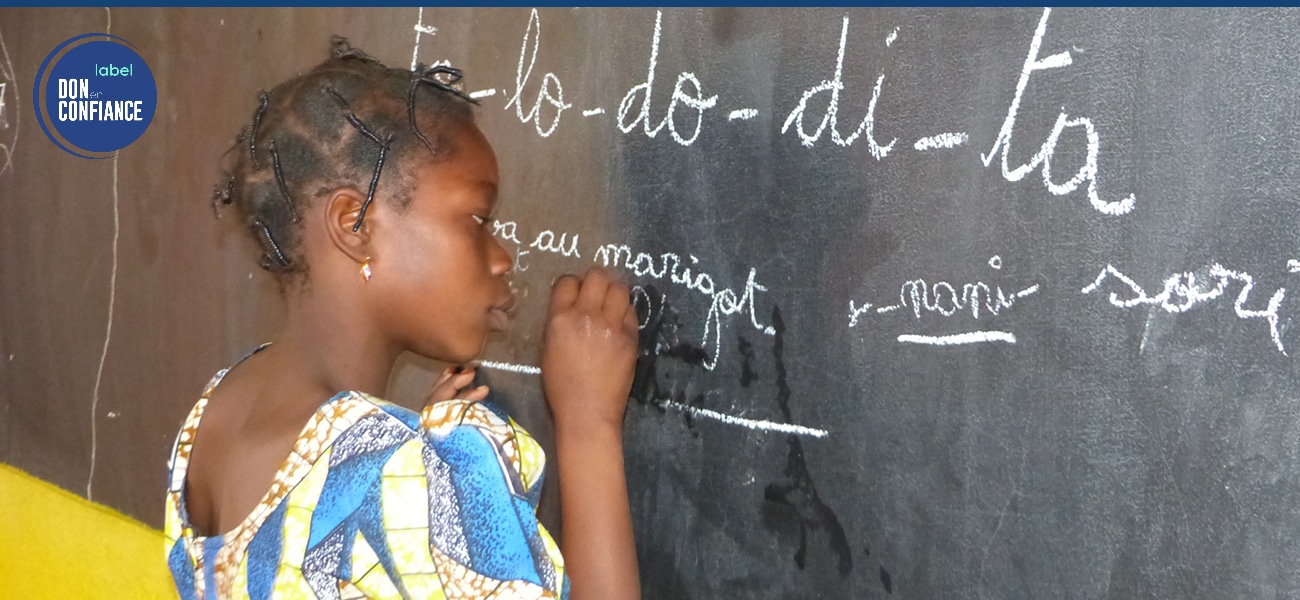 Jeune fille du Burkina Faso qui écrit sur un tableau noir à l'école