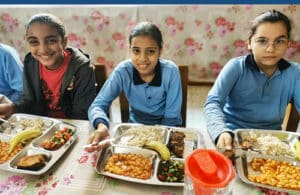 Trois jeunes filles bénéficiaires de l'AHEED en train de prendre un repas